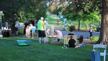 Guests can enjoy a lively outdoor gathering on the lush lawn, complete with a table for activities and games.