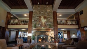 A spacious living area with a stone fireplace, leather sofas, and a wooden balcony. - Running Y Resort (Klamath Falls)
