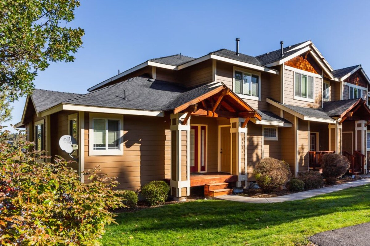 A two-story house with a front porch, a garage, and a well-maintained lawn.