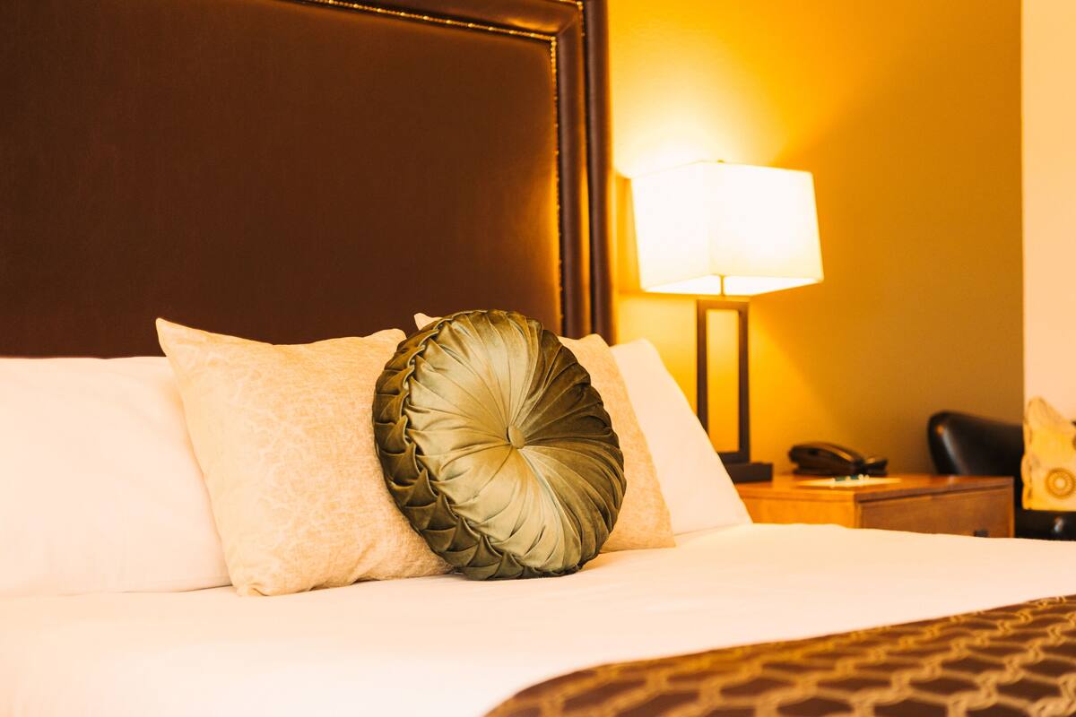 A hotel room with a bed, a nightstand, a lamp, and a telephone.