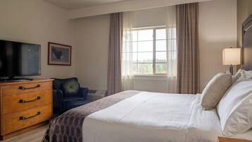 Een hotelkamer met een bed, een televisie, een bureau, een stoel en een raam met gordijnen.