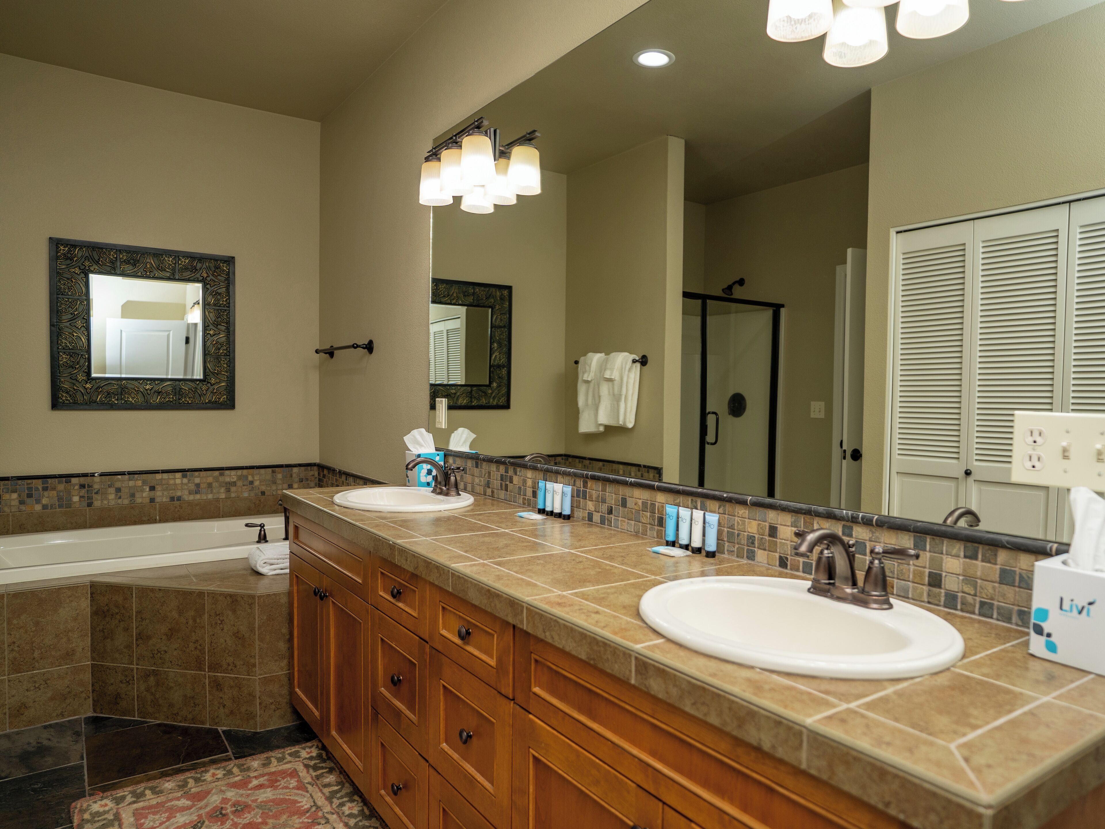 A bathroom with two sinks, a bathtub, a shower, and a large mirror.