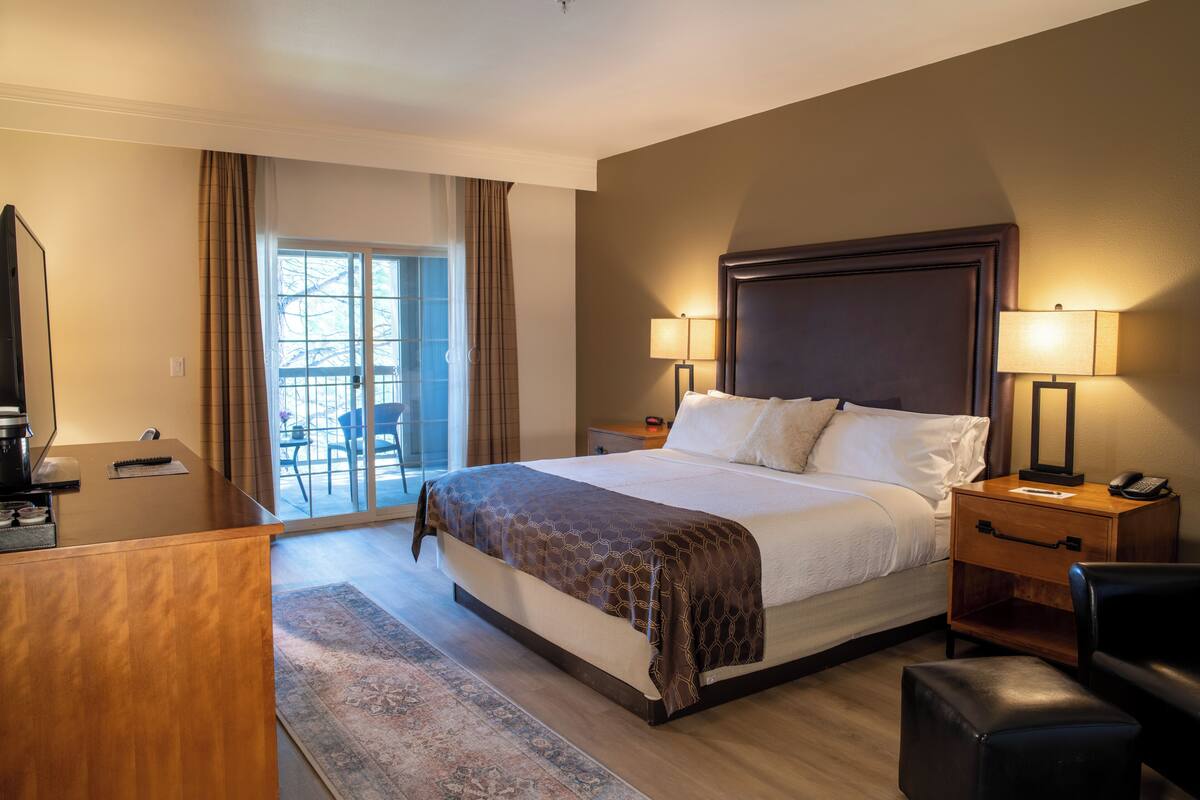 A hotel room with a bed, bedside tables, a desk, and a chair.