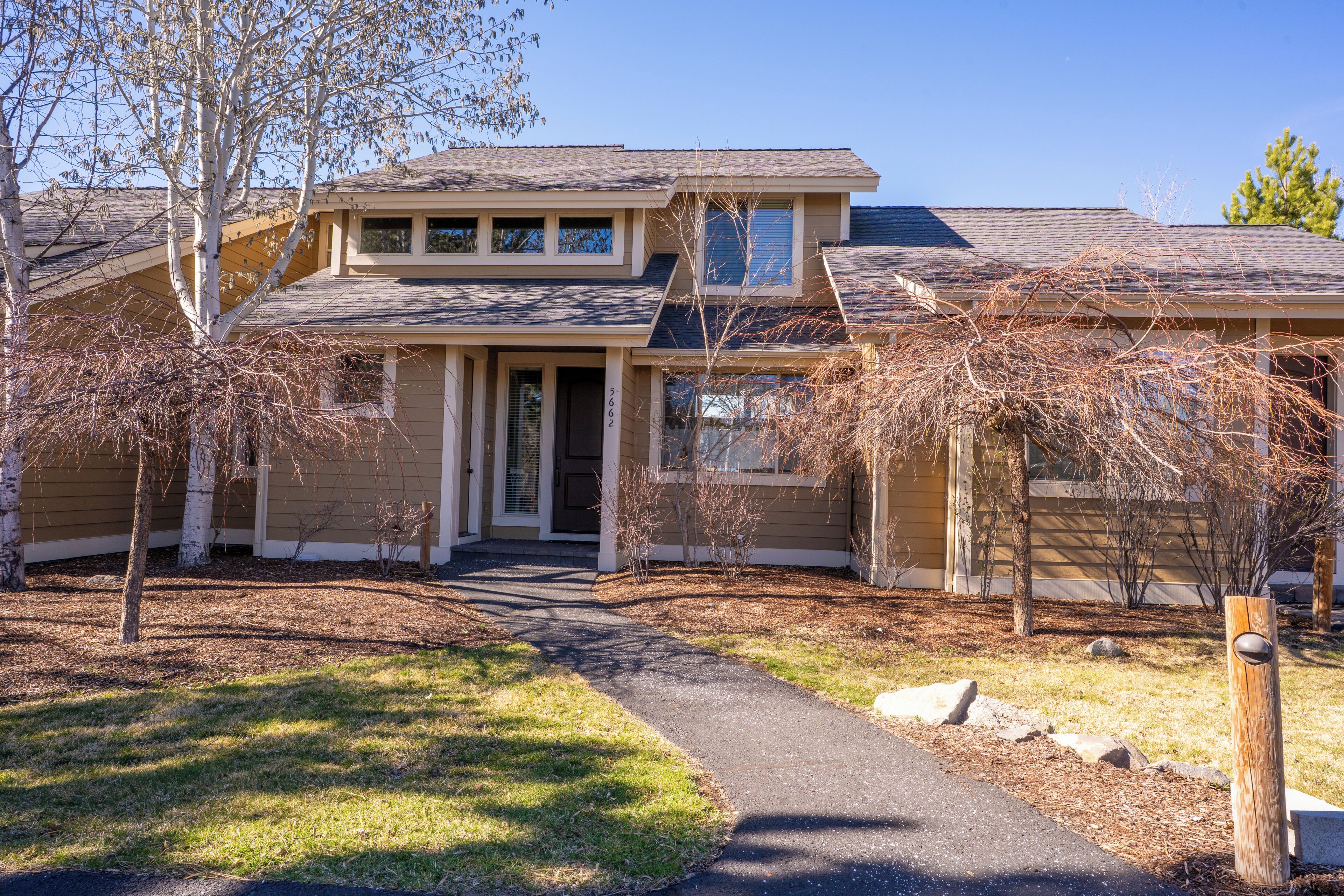 A two-story house with a front porch, a driveway, and a well-maintained lawn.