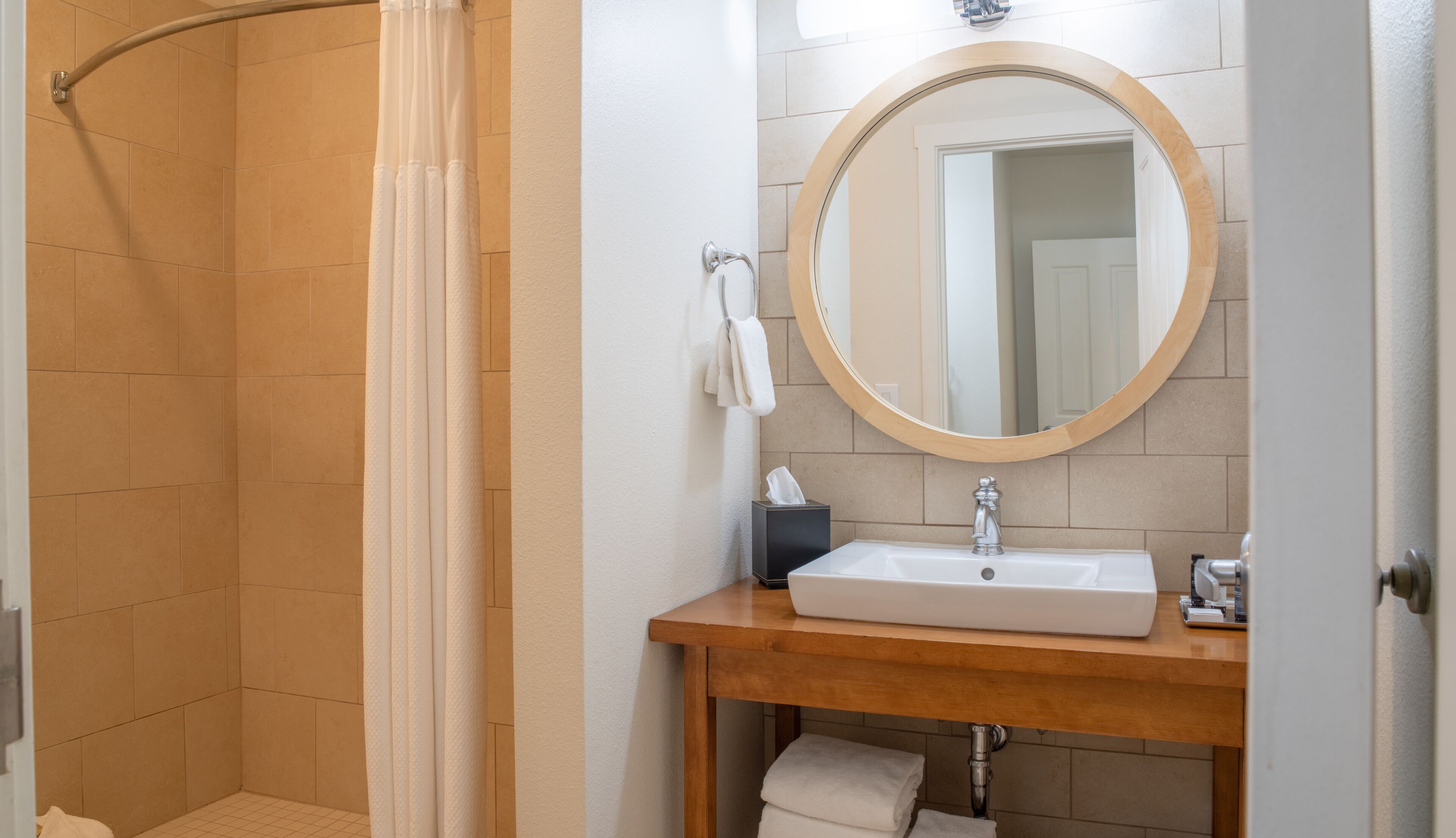Un bagno con doccia, lavandino con specchio e porta asciugamani.
