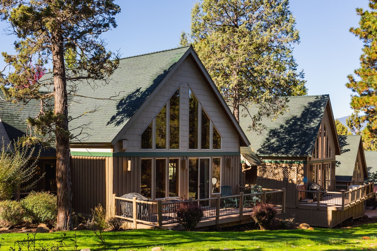 A lodge with a prominent gable roof, a covered deck, and a well-maintained lawn.