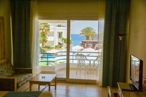 A room with a balcony, a sofa, a table, and a TV. - Queen Sharm Resort (Sharm El Sheikh)