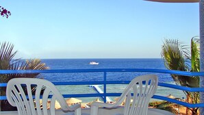 Un balcon avec deux chaises en plastique blanches donnant sur une vue de l’océan.