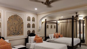 A hotel room with two beds, a canopy bed, decorative wall panels, and a ceiling fan.