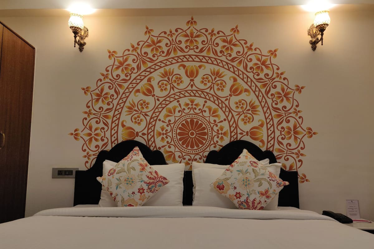 Una cama con un cabecero decorativo, dos luces fijadas en la pared y un diseño de pared con estampado.
