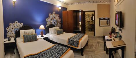 A hotel room with two beds, a desk, a TV, and a wardrobe.