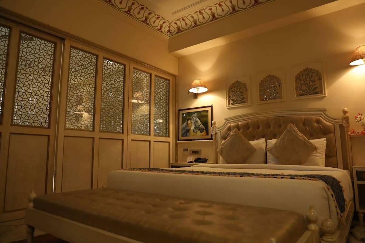A bedroom with a large bed, a bedside table, a nightstand, and a wall-mounted lamp.