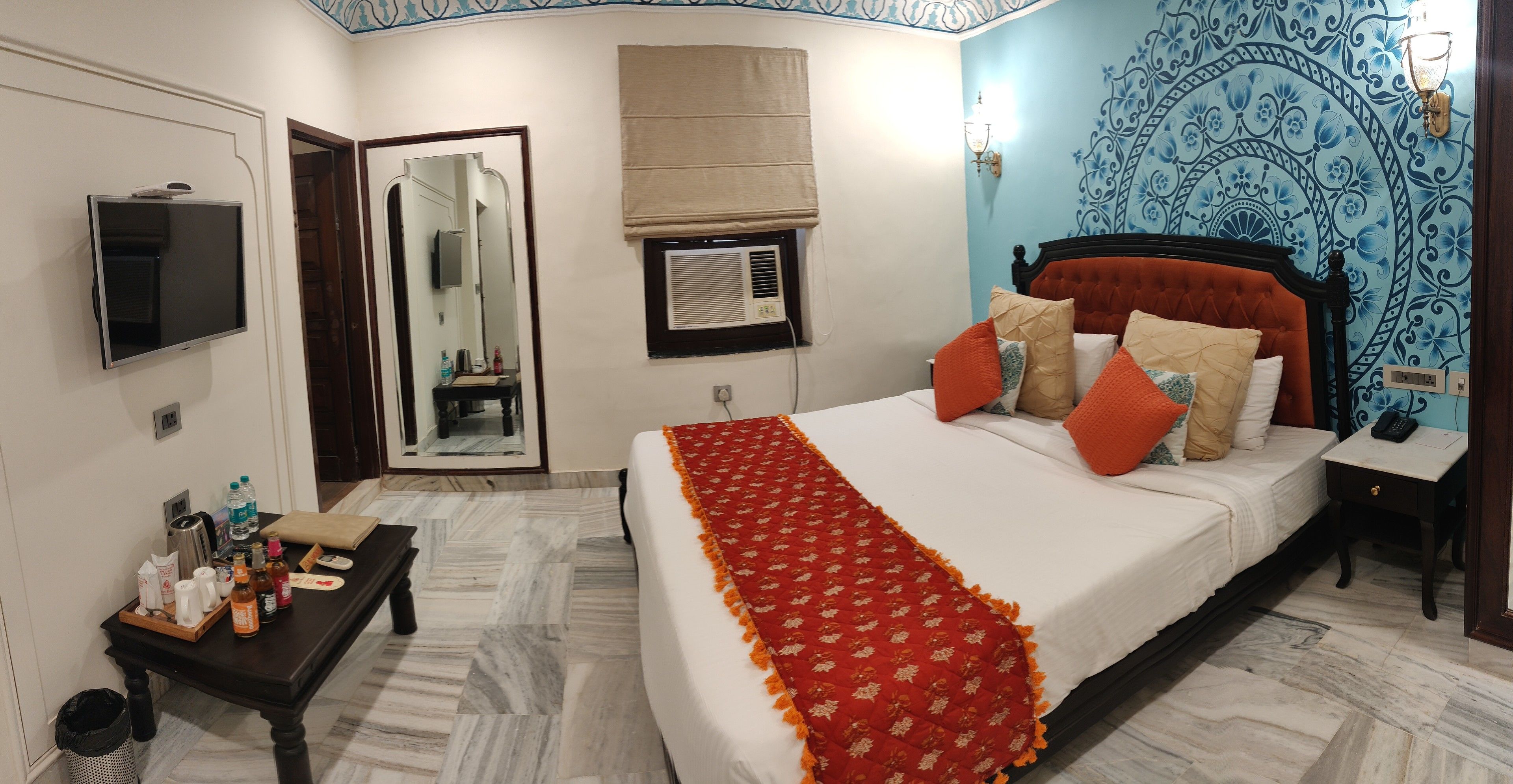 A bedroom with a bed, bedside table, and a mirror.