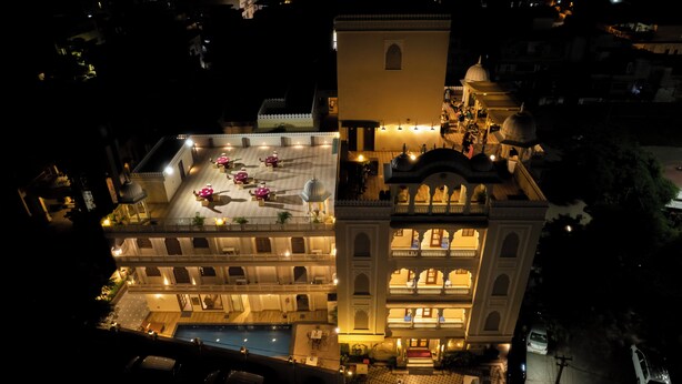 A multi-story hotel with a pool, outdoor seating area, and traditional architecture.