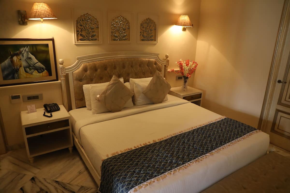 Habitación de hotel con una cama grande, dos mesitas de noche, un teléfono y decoración en la pared.