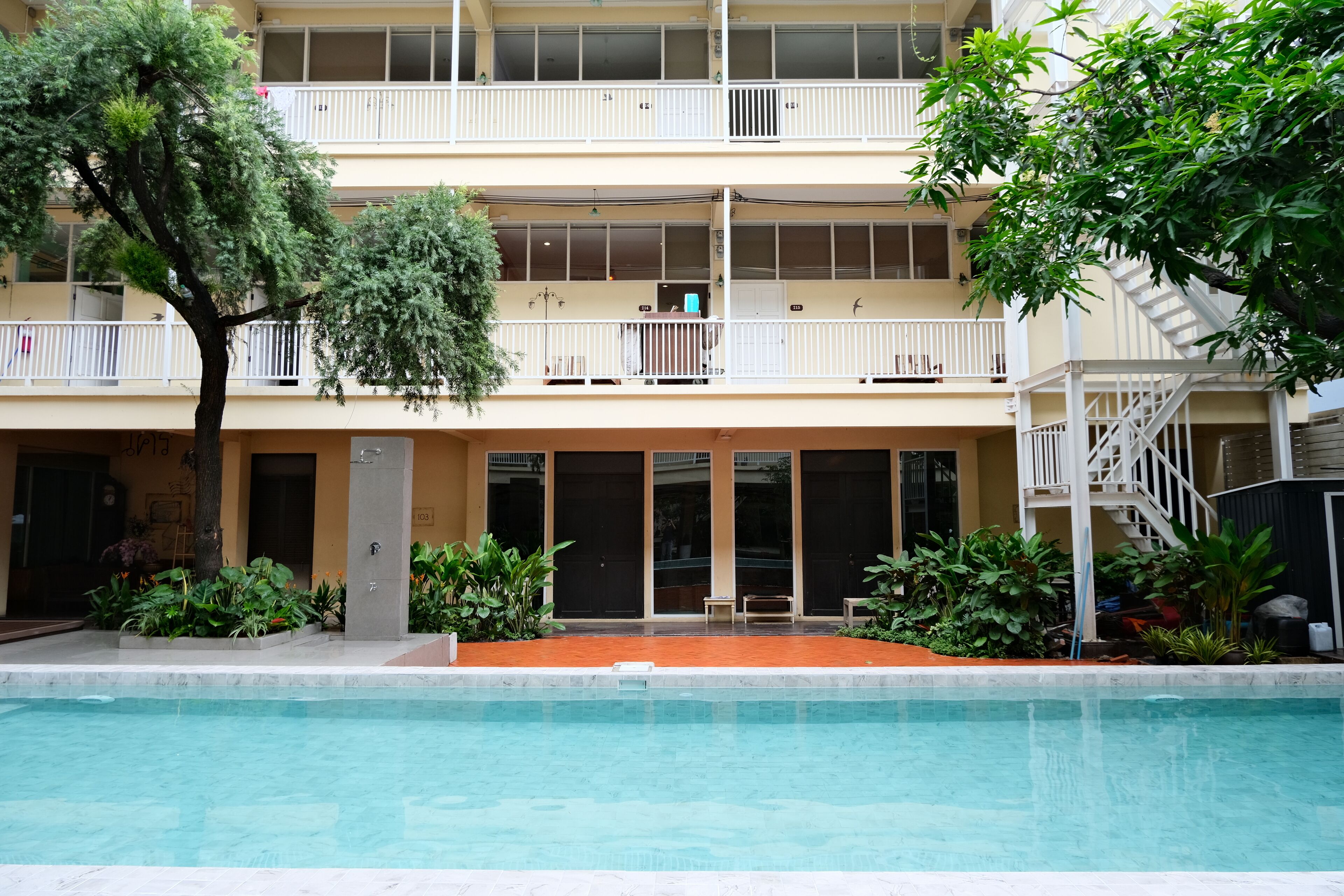 A multi-story building with a swimming pool, balconies, and a staircase.