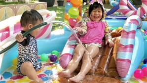 A child and an adult in an inflatable pool with colorful balls and a water hose. - Feung Nakorn Balcony Rooms and Cafe (Bangkok)