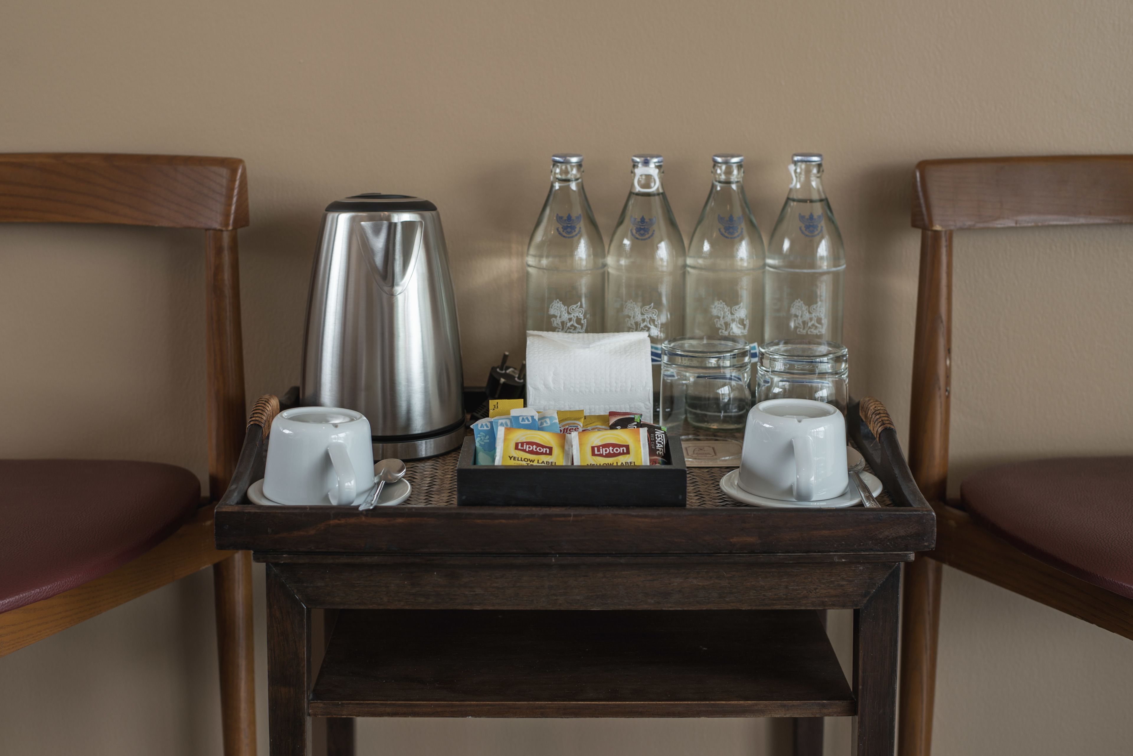 Un chariot de service pour le petit-déjeuner contenant une machine à café, des tasses, des sachets de thé Lipton et des bouteilles d’eau.