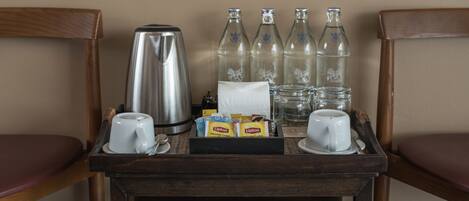 A breakfast trolley with a coffee maker, cups, Lipton tea bags, and bottled water.