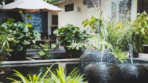 A koi pond with water fountains and potted plants in a courtyard. - Feung Nakorn Balcony Rooms and Cafe (Bangkok)