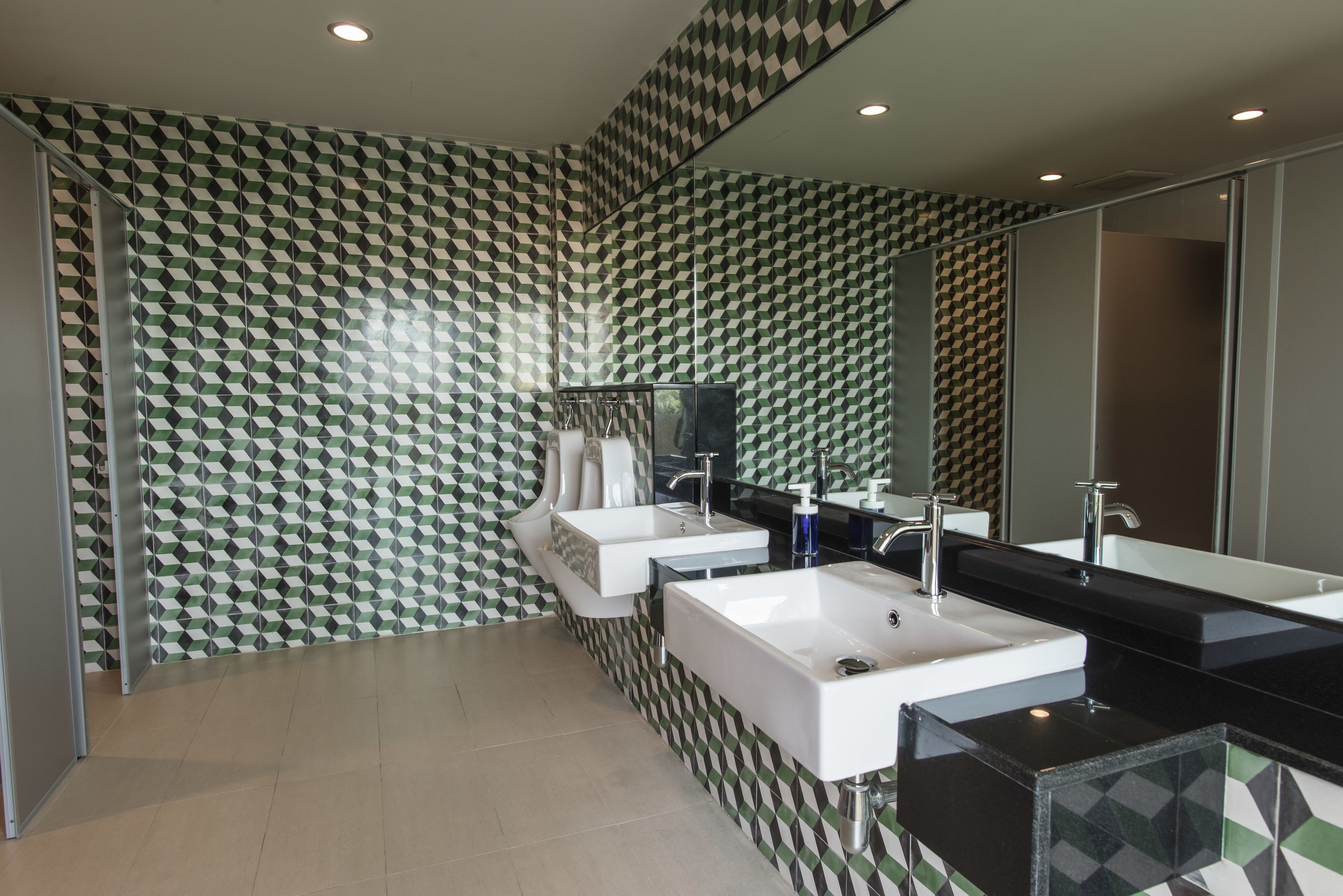 A modern bathroom with a geometric patterned wall, two sinks, a large mirror, and a bathtub.