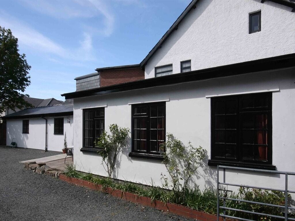 A white building with black-framed windows and a brick roof.