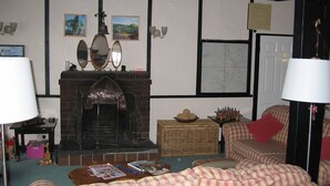 A cozy living room with a fireplace, checkered sofas, and a bookshelf.