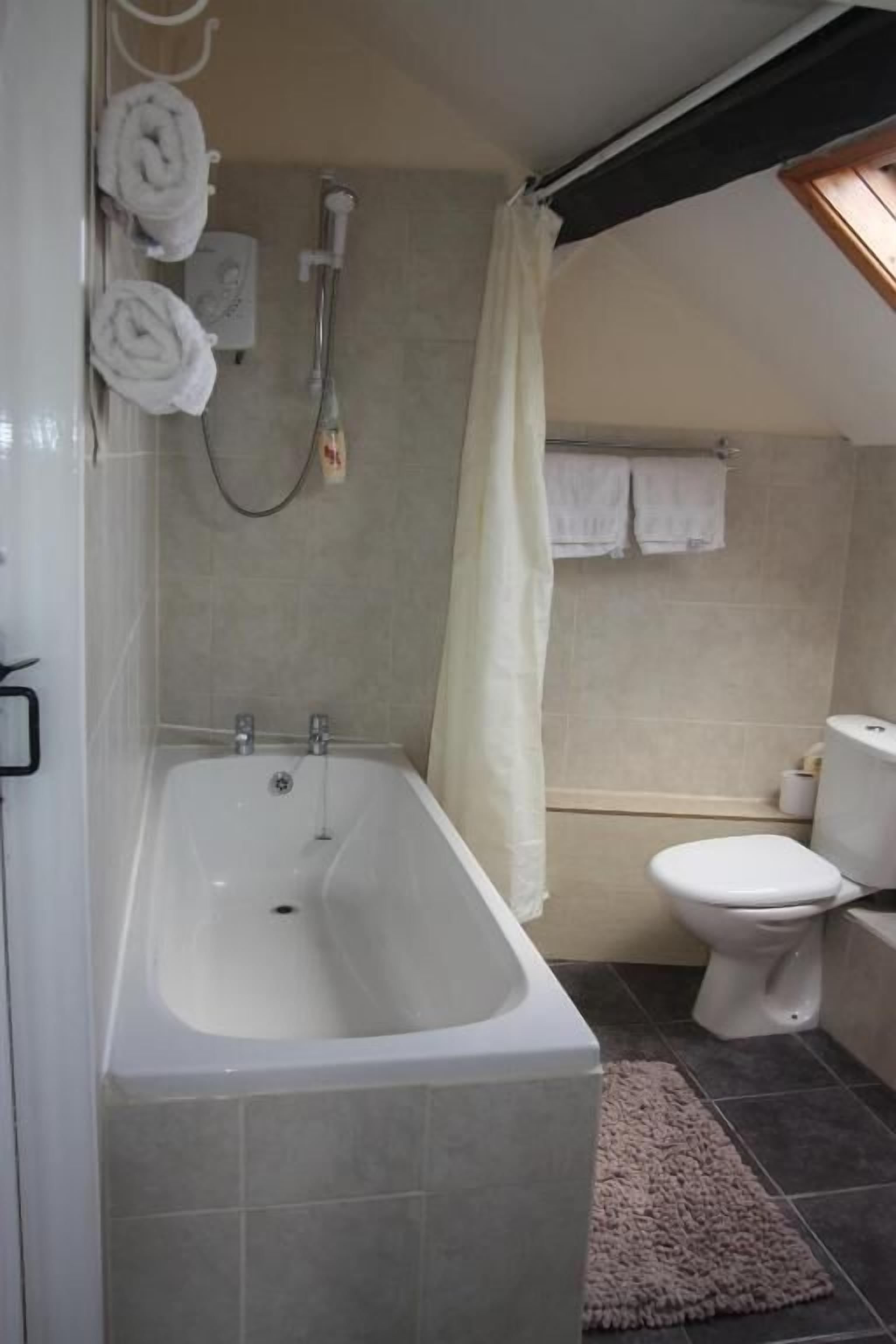 A bathroom with a bathtub, toilet, and shower.