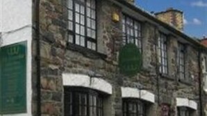 A stone building with multiple windows and a green sign.