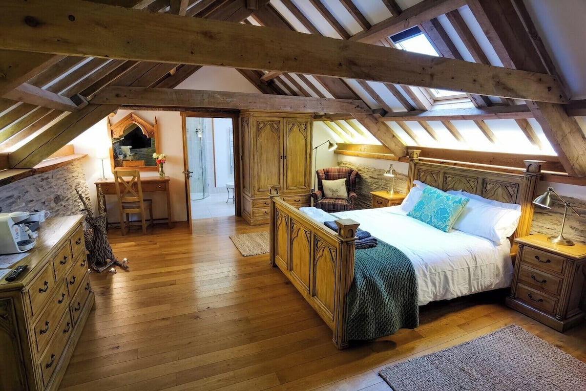Une chambre mansardée chaleureuse, avec un lit en bois, un bureau et une chaise.