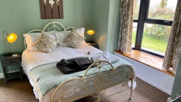 A bedroom with a bed, two bedside tables, a window with curtains, and a wall-mounted picture.