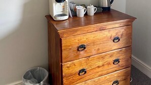 Ein hölzerner Nachttisch mit Kaffeemaschine und Wasserkocher darauf.