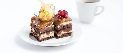 Un postre con caramelo y bayas sobre un plato blanco, junto a una taza blanca.