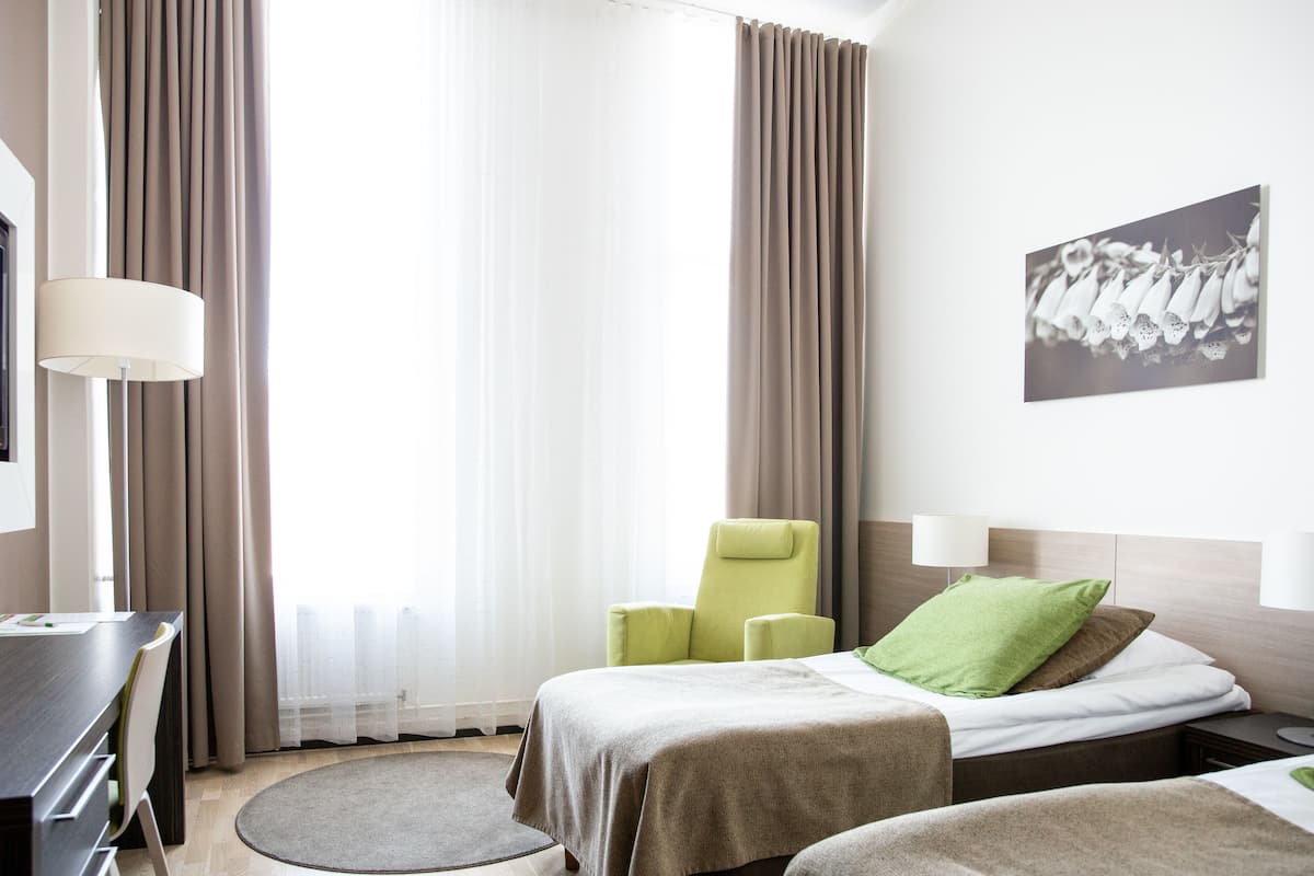 Une chambre d’hôtel avec un lit, une chaise, un bureau et une lampe.