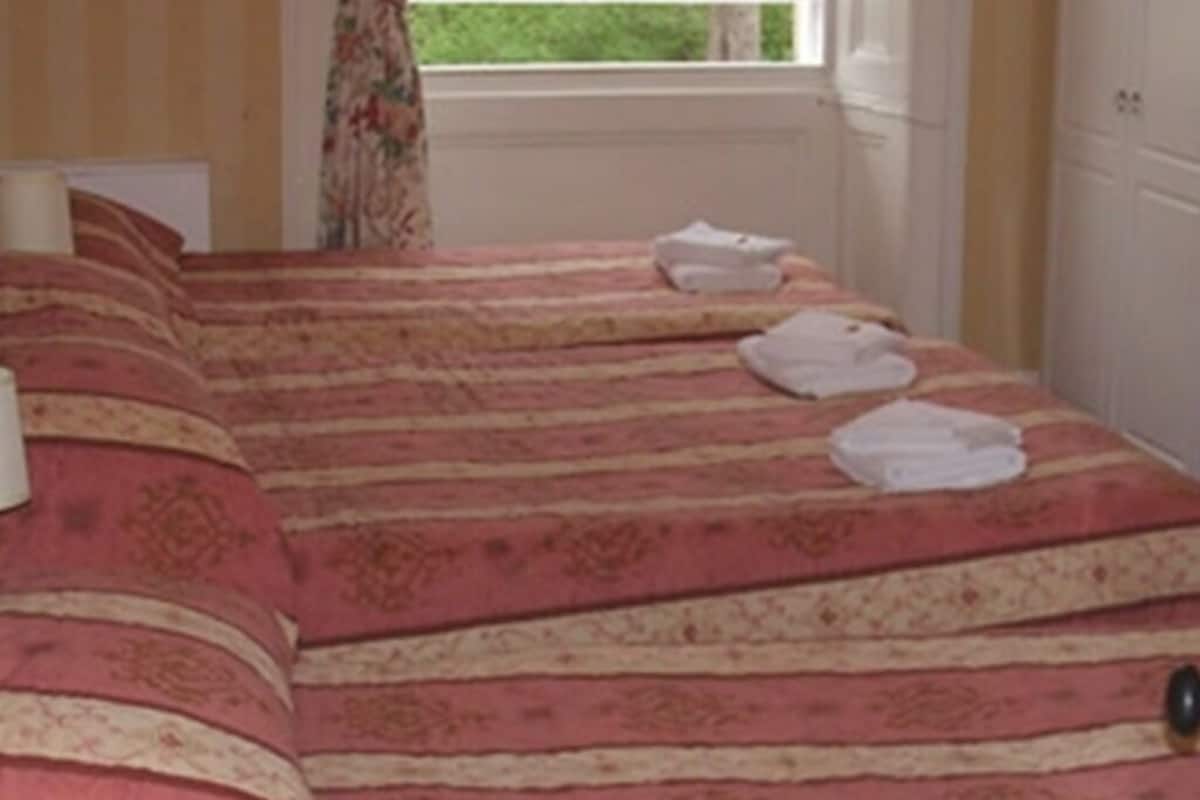 A bed with a striped bedspread and two folded towels on it.