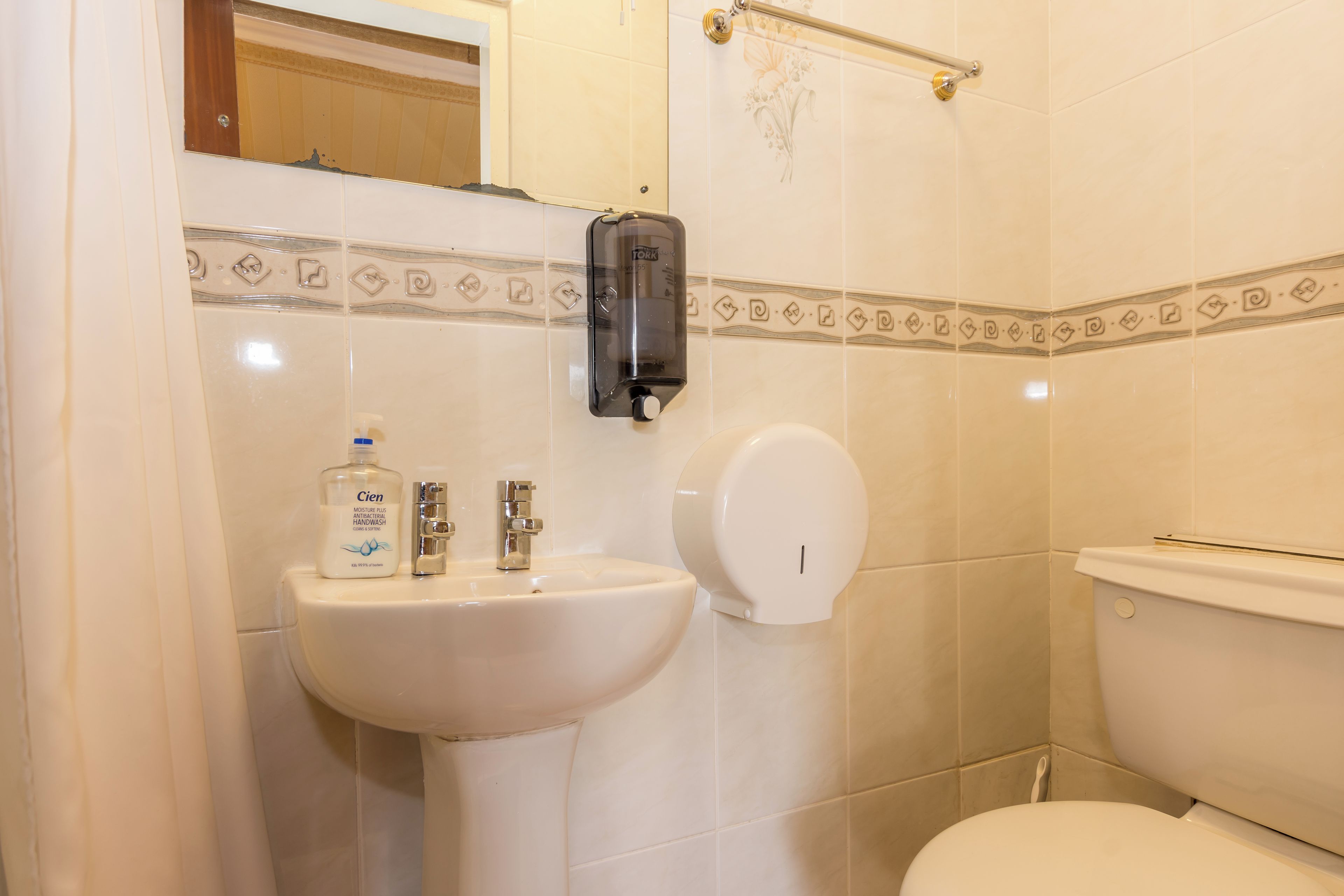 A bathroom with a sink, a toilet, and a hand dryer.