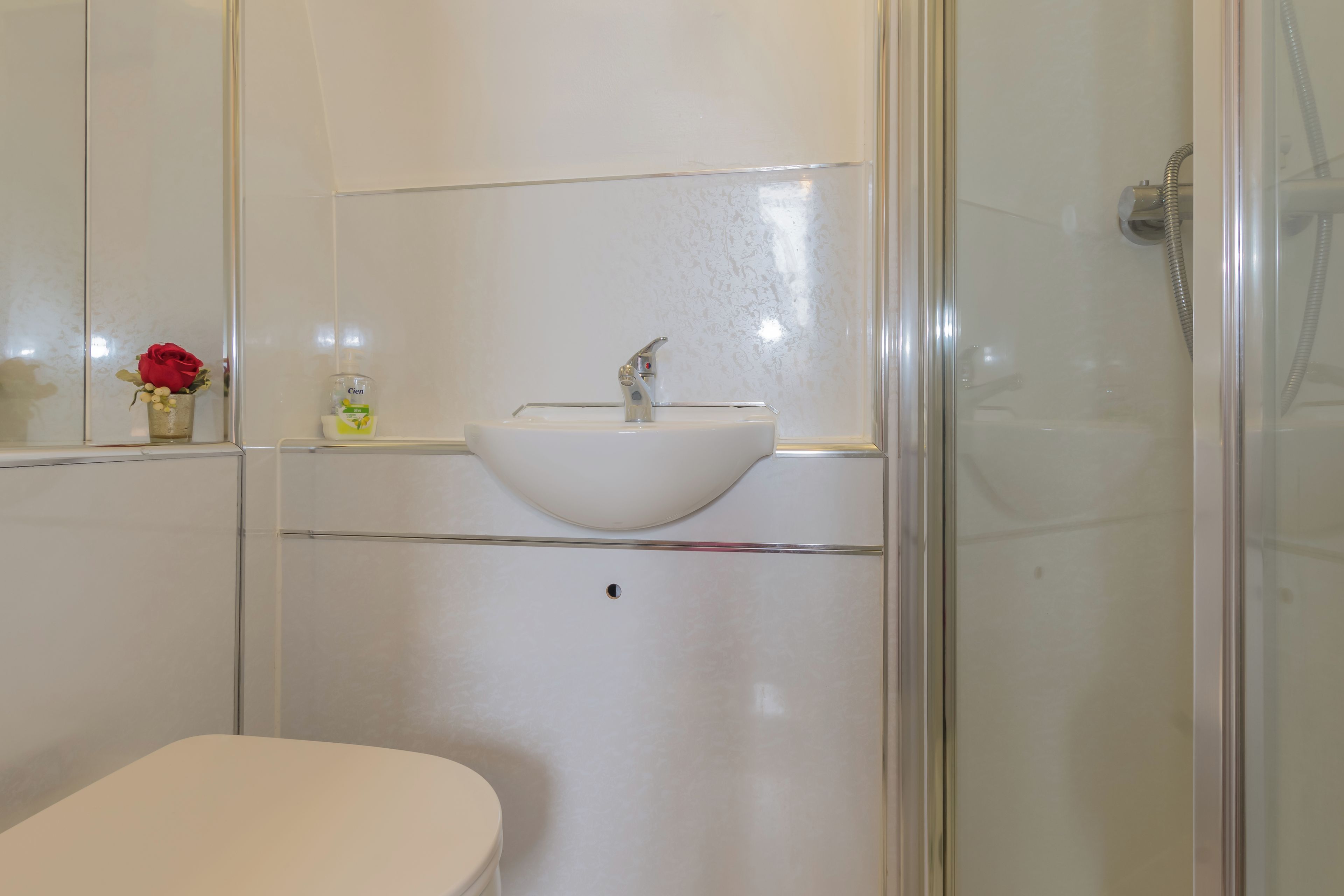 A bathroom with a white sink, a toilet, and a glass shower enclosure.