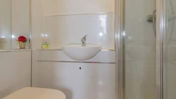 A bathroom with a white sink, a toilet, and a glass shower enclosure.