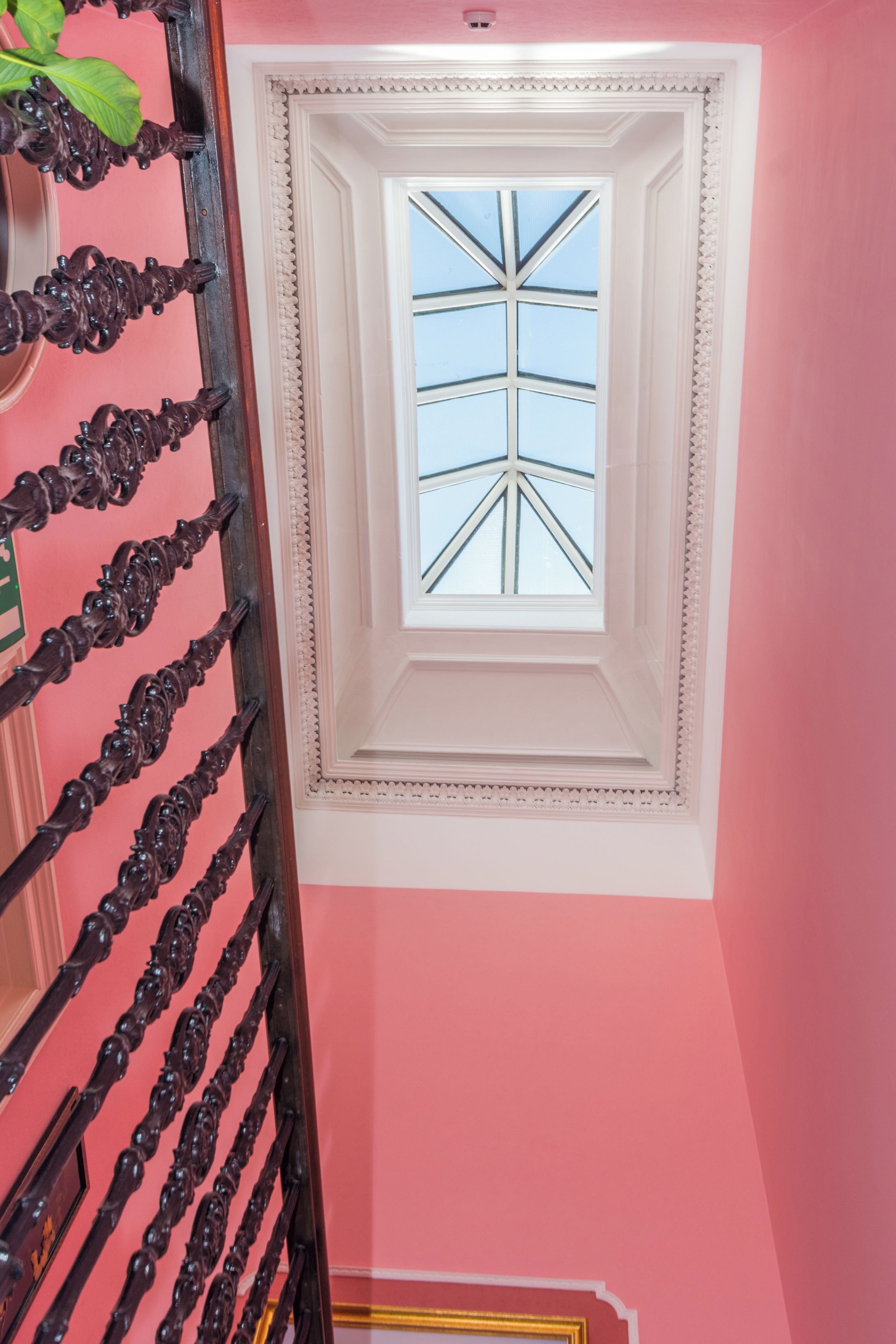 A staircase with ornate black railings leading to a room with a skylight.