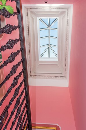 Una escalera con barandillas negras ornamentadas que conduce a una habitación con tragaluz.