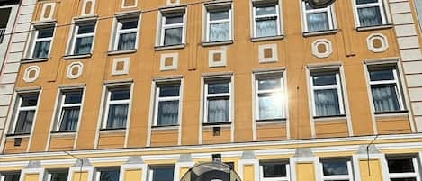 Un immeuble à plusieurs étages, doté d’une façade jaune, de nombreuses fenêtres et d’une entrée centrale sur laquelle est apposée une enseigne indiquant « Klimt ».