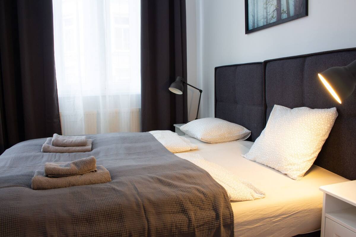 A neatly made bed with a checkered bedspread, two pillows, and two folded towels.