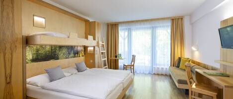 A modern hotel room with a large bed, a desk, and a TV.