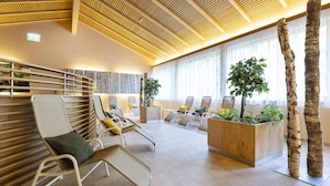 A modern waiting area with lounge chairs, a wooden reception desk, and a large plant.