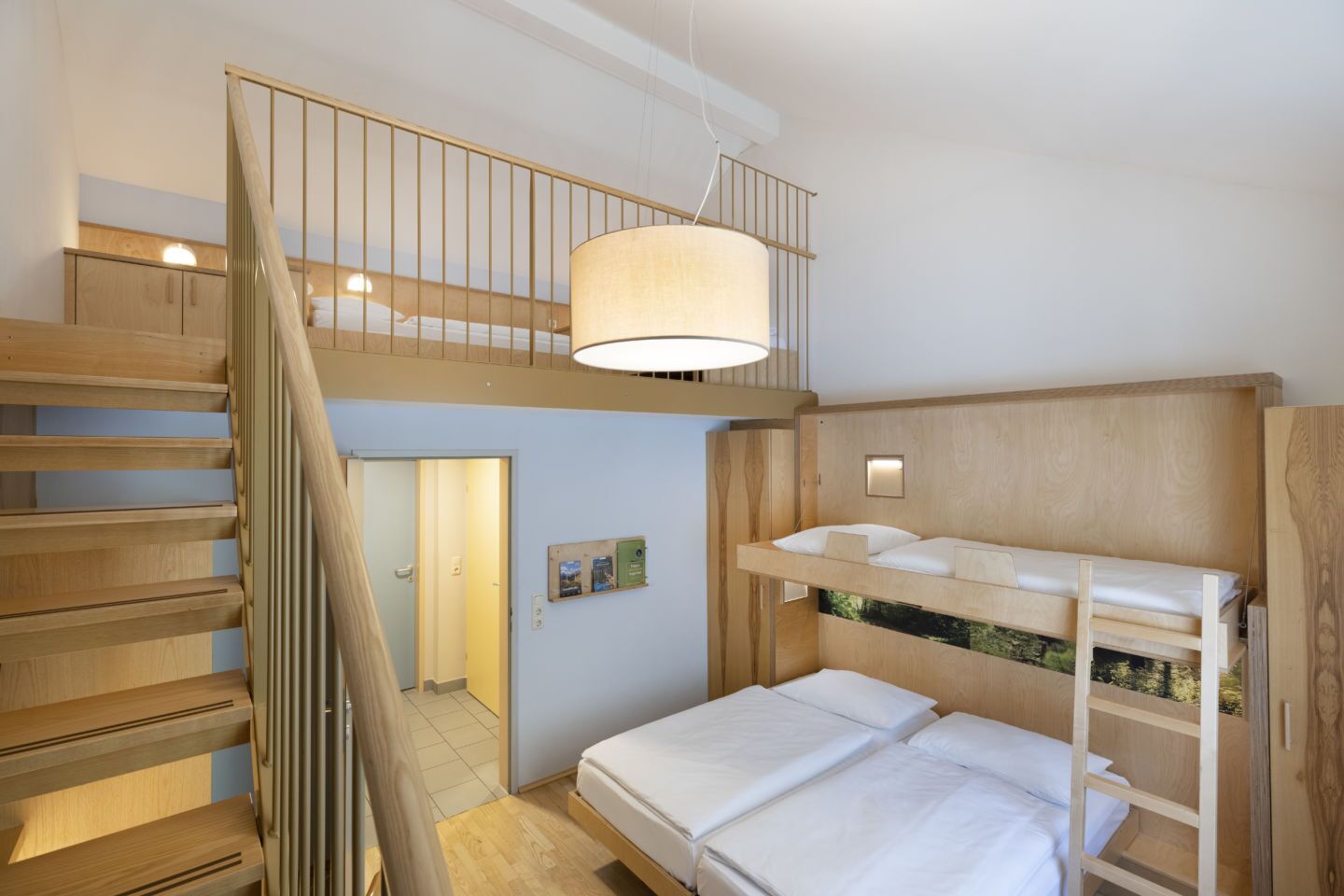 Een kamer met meerdere niveaus, inclusief stapelbedden, een trap en een hangende lamp.
