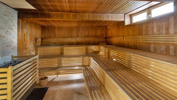 A sauna with wooden benches and a stone wall.