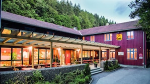 A hotel with a covered outdoor seating area and a red exterior.