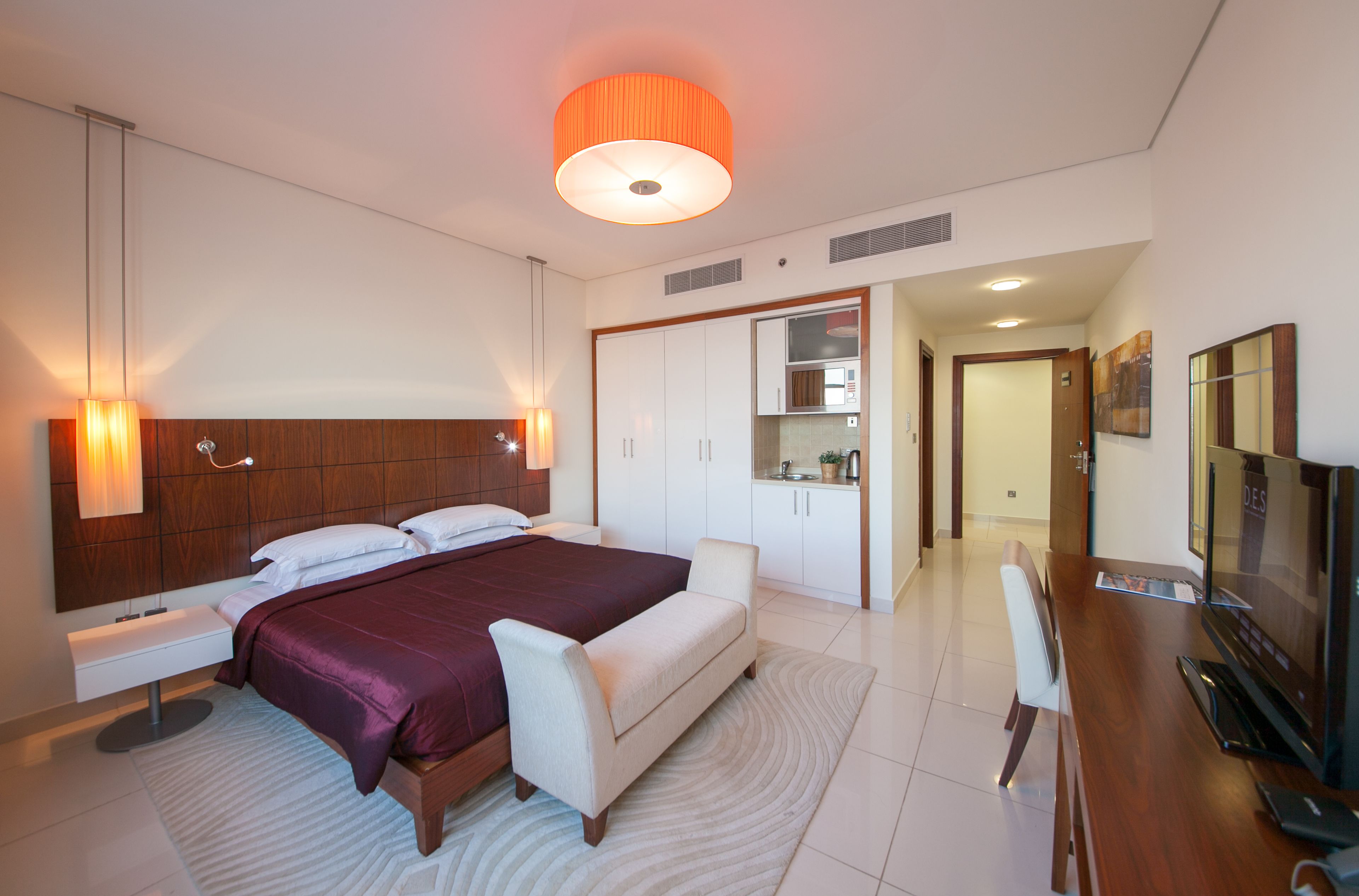 A modern bedroom with a large bed, bedside tables, a desk, and a television.