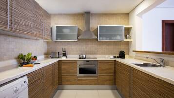Una cocina moderna con armarios de madera, horno empotrado, pileta de acero inoxidable y microondas.