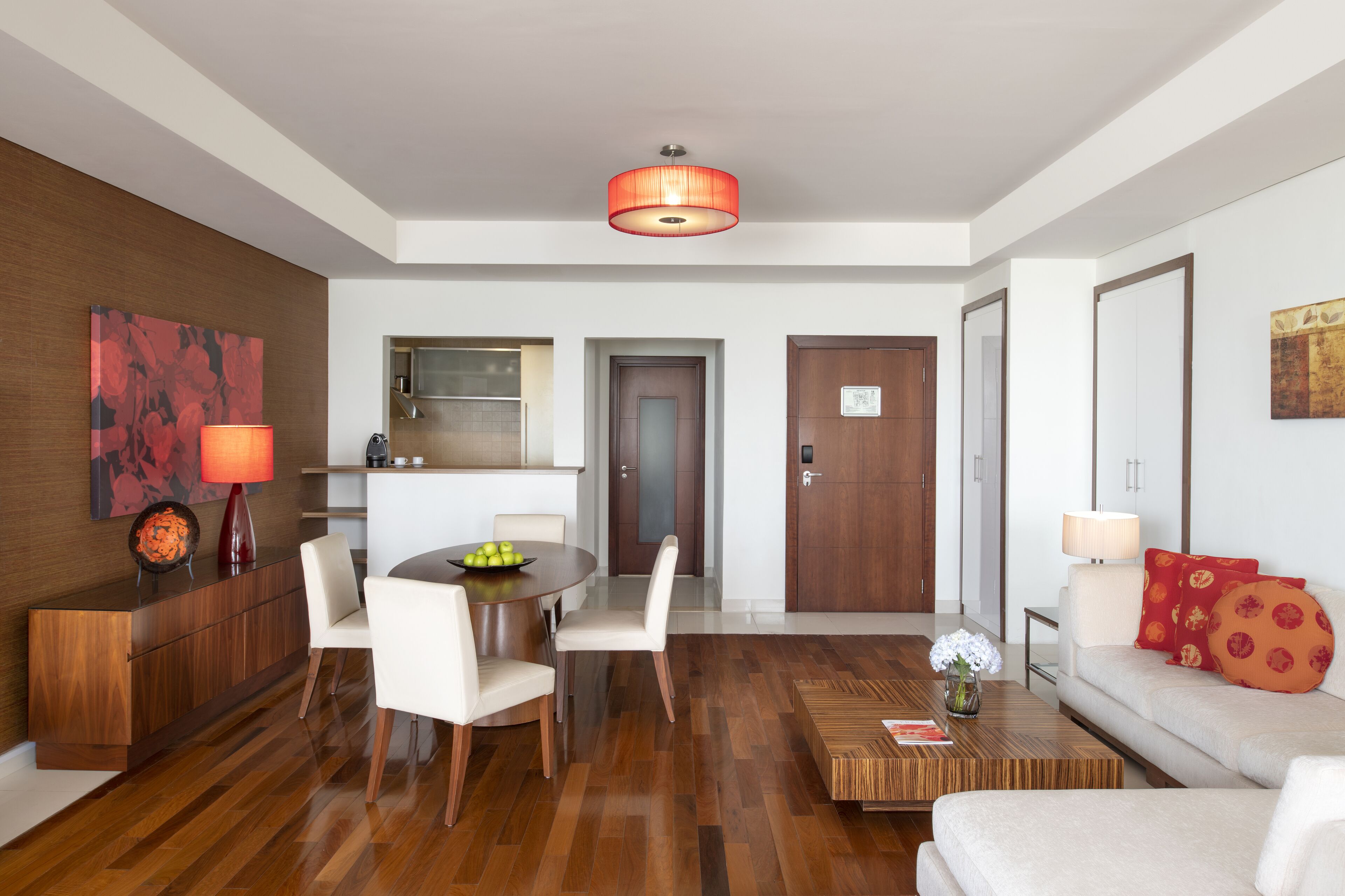 A modern hotel room with a dining area, a sofa, and a wooden coffee table.